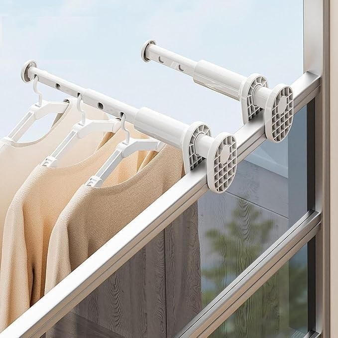 Clothes drying rack with clothes hanging on it next to a window