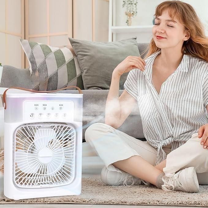 Woman sitting on a rug with a white box fan in front of her in a cozy living room.