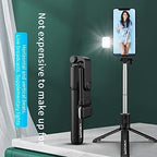 Black selfie stick with smartphone holder and light on a white surface with green background
